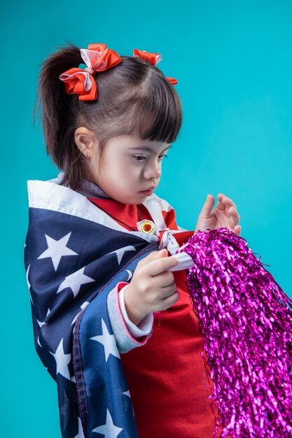 Decorazione del 4 luglio. Ragazzo carino mantenendo il pompon viola brillante e essendo vestiti nella bandiera degli Stati Uniti