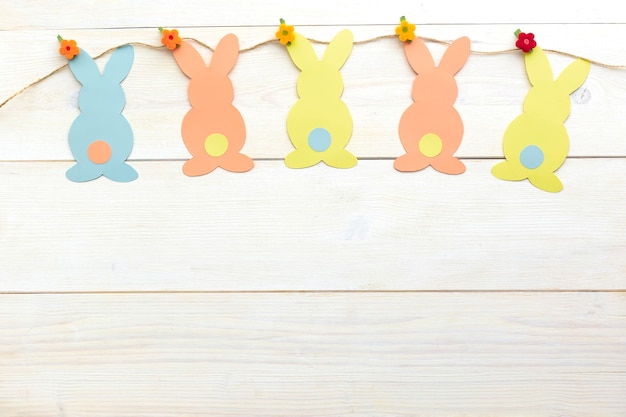 Decorazione del coniglietto di Pasqua. Carta tagliata fai da te vacanza conigli colorati.Vista dall'alto, copia spazio bianco su sfondo di legno.