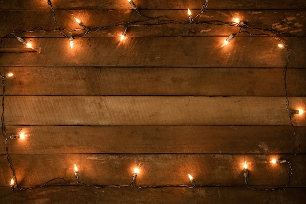 Decorazione della lampadina delle luci di Natale sulla vecchia plancia di legno, confine della struttura