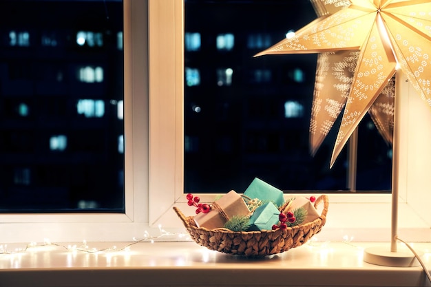 Decorazione della stanza di Natale Cesto con regali luce notturna stellare e ghirlanda luminosa sulla finestra notturna