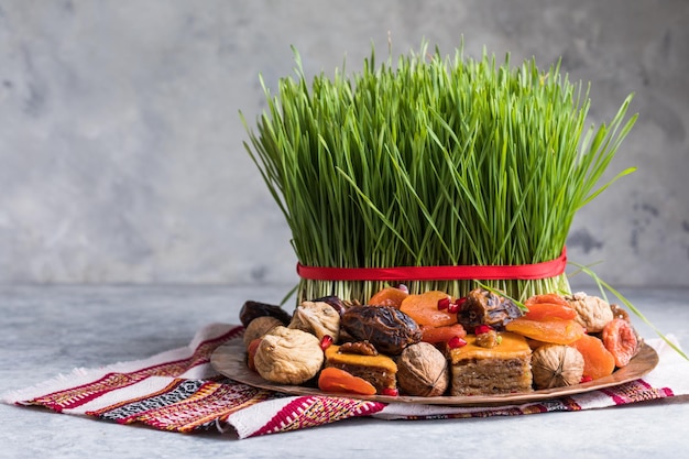 Decorazione della tavola di Novruz, erba di grano, pakhlava di pasticceria nazionale dell'Azerbaigian, celebrazione del nuovo anno, risveglio della natura