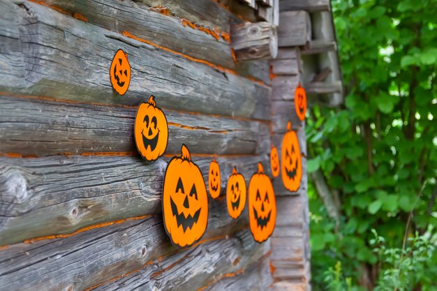 Decorazione di Halloween all'aperto. Ghirlanda di carta con zucche carine appese alla parete in legno del vecchio edificio del bagno pubblico nel villaggio.