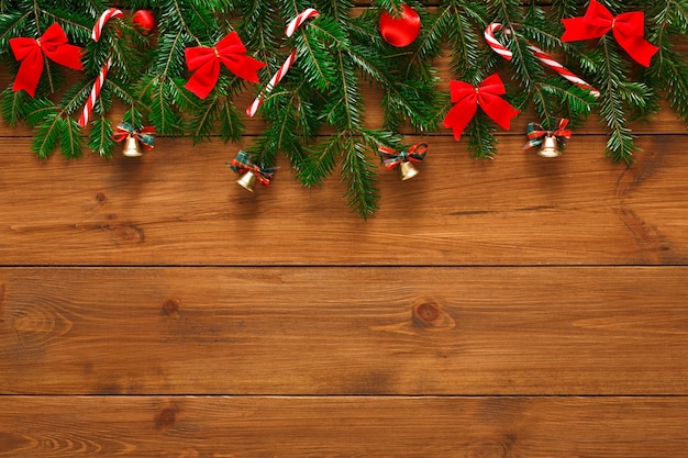 Decorazione di Natale, campane, fiocchi e ghirlanda concetto cornice sfondo, vista dall'alto con copia spazio sulla superficie del tavolo in legno rustico. Bordo addobbi natalizi con rami di abete