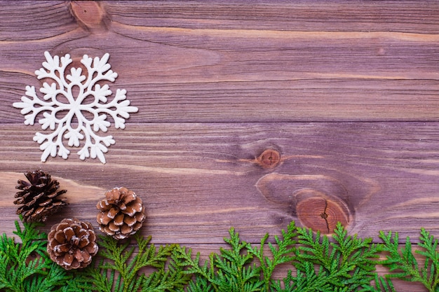 Decorazione di Natale con rami di thuja, fiocco di neve e pigne sul tavolo di legno.