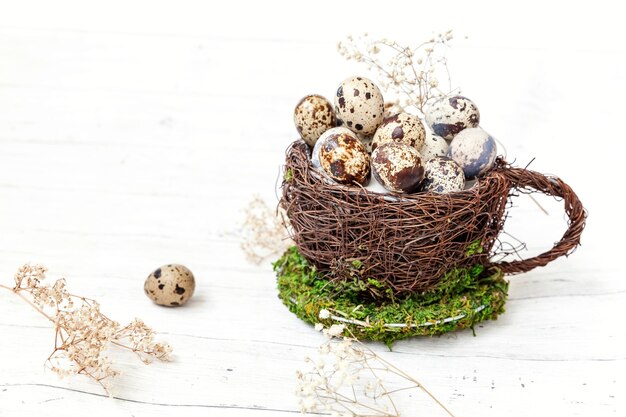 Decorazione di Pasqua con l'uovo nella tazza del nido su fondo di legno bianco