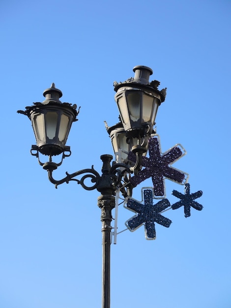 Decorazione di strada di Natale sui lampioni contro il cielo blu