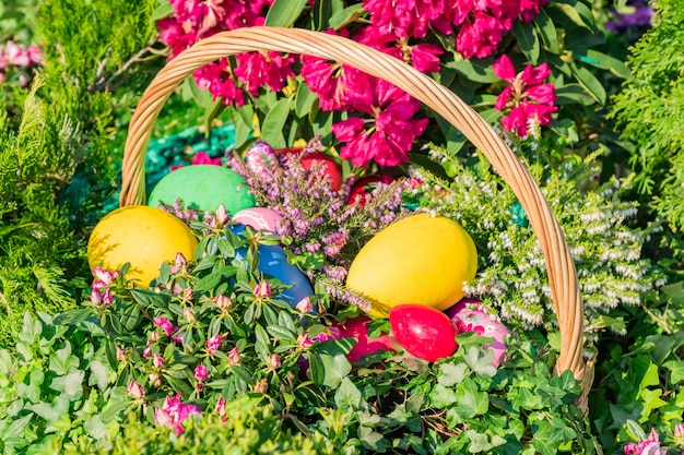 Decorazione di strada di Pasqua. Cesto di vimini pieno di uova di Pasqua dipinte, torta e fiori.