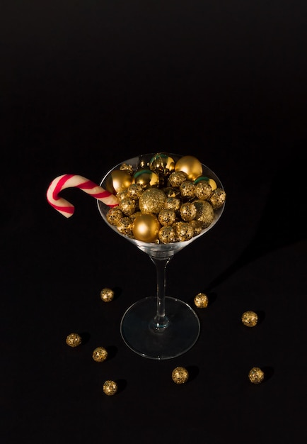 Decorazione dorata delle palline di Natale nel bicchiere da martini su sfondo nero Concetto di festa di capodanno