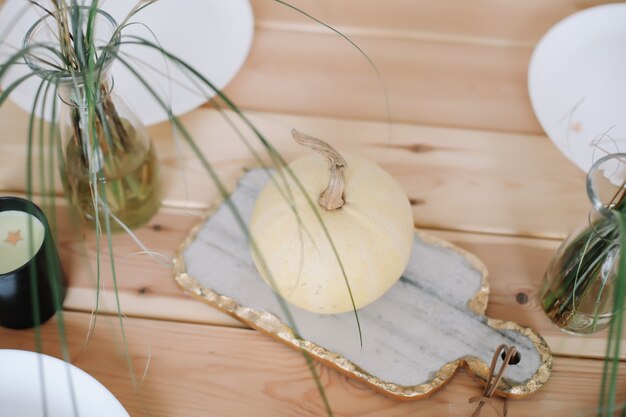 Decorazione festiva della tavola autunnale con piatti di zucche bianche e candele sulla vista del piano del tavolo in legno