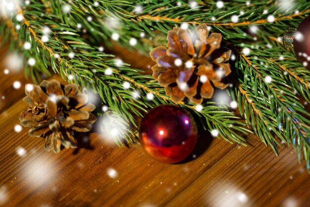 decorazione natalizia, vacanze, capodanno e concetto di arredamento - primo piano di ramo di abete naturale, palla e pigna su tavolo di legno
