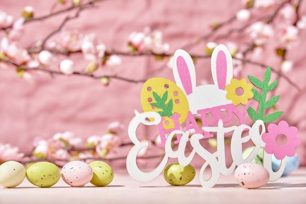 Decorazione pasquale con coniglietto di uova di Pasqua e fiori di ciliegio su sfondo rosa Buona Pasqua