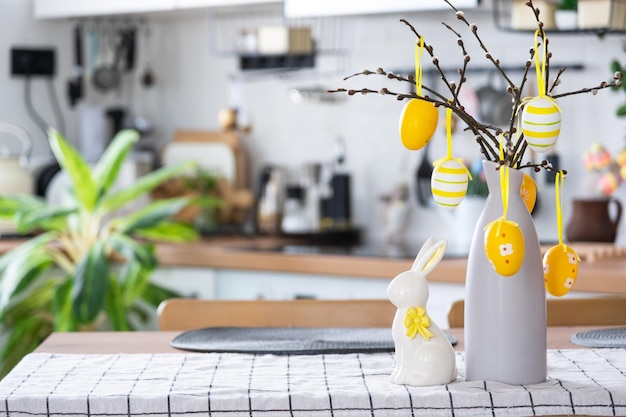 Decorazione pasquale di uova colorate in un cesto e un coniglio sul tavolo della cucina in stile rustico Interno festivo di una casa di campagna