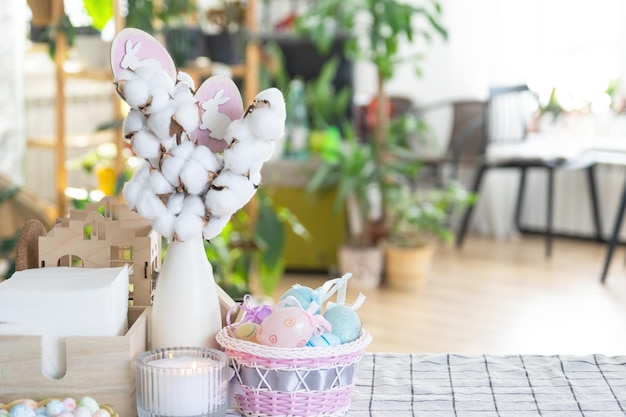 Decorazione pasquale di uova colorate in un cesto e un coniglio sul tavolo della cucina in stile rustico Interno festivo di una casa di campagna