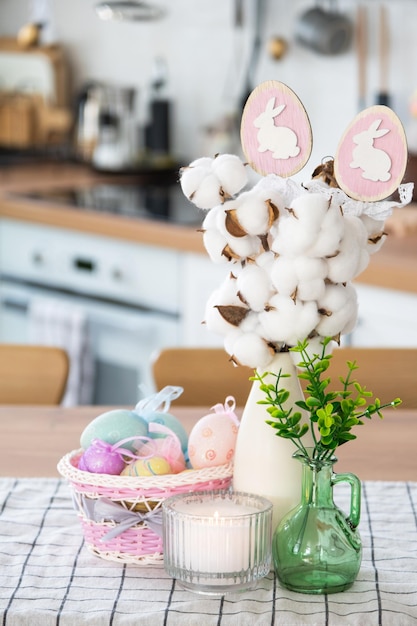 Decorazione pasquale di uova colorate in un cesto e un coniglio sul tavolo della cucina in stile rustico Interno festivo di una casa di campagna