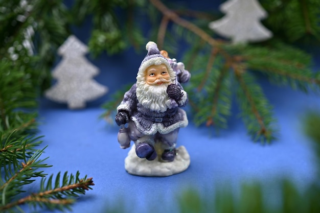 Decorazione per la casa di Capodanno statuetta di Babbo Natale in un abito blu tra i rami di abete