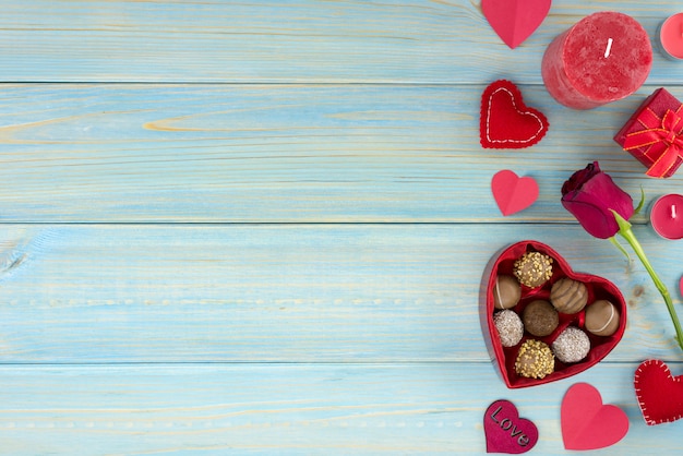Decorazione romantica di giorno di San Valentino con rose e cioccolato su un tavolo di legno blu.
