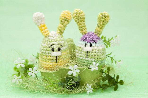 Decorazioni a maglia di uova di Pasqua, fiori, coniglietto su uno sfondo verde, amigurumi