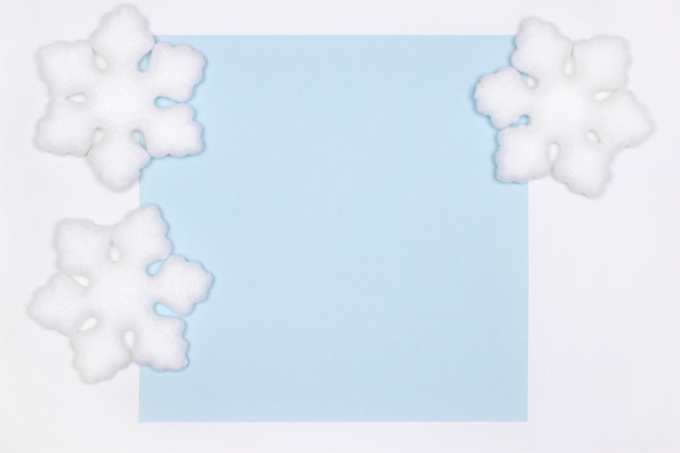 Decorazioni bianche a fiocco di neve su carta di carta blu distesa piatta. Copia spazio. Semplice sfondo invernale