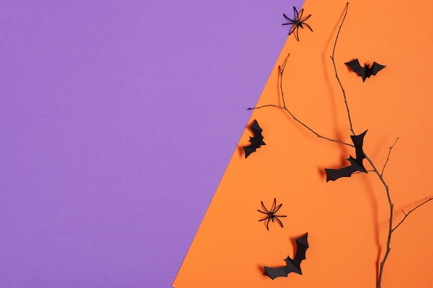 Decorazioni di Halloween pipistrelli di carta che volano sul ramo di un albero e ragni su sfondo viola e arancione