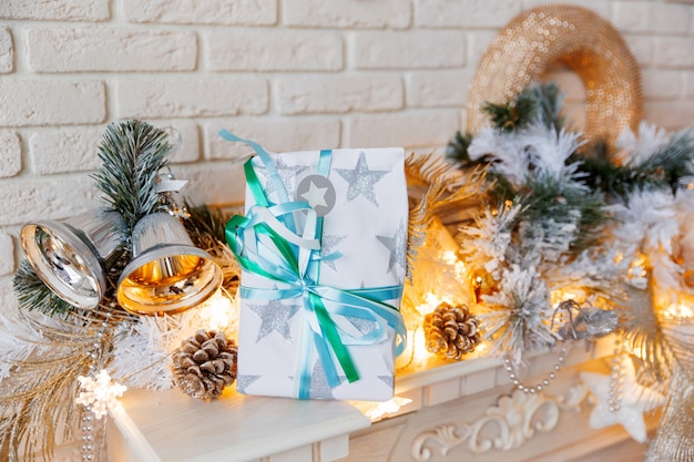 Decorazioni di Natale e Capodanno su caminetto. Priorità bassa di inverno di festa con presente avvolto. Regalo con fiocco in carta.