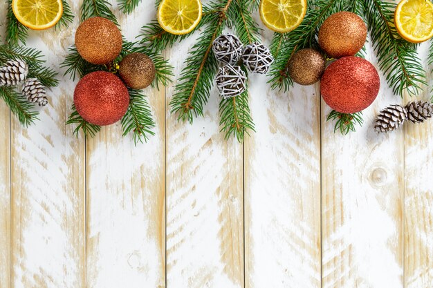 Decorazioni di natale, sfere arancioni e frutta arancione su una tabella di legno bianca. Vista dall'alto, copia spazio.