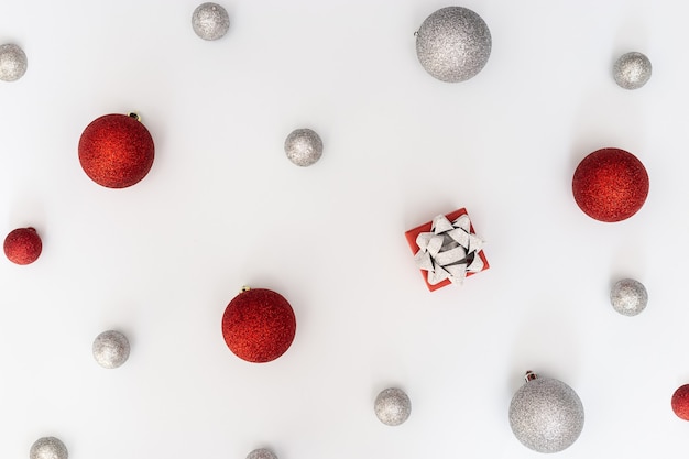 Decorazioni di palline di Natale palline colorate di rosso e argento e confezione regalo su sfondo bianco