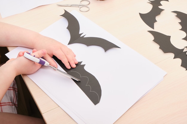 Decorazioni fatte a mano di Halloween. bambino taglia un pipistrello di carta nera