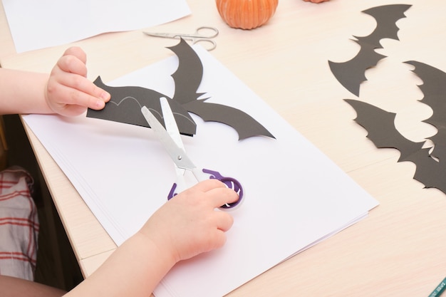 Decorazioni fatte a mano di Halloween. bambino taglia un pipistrello di carta nera