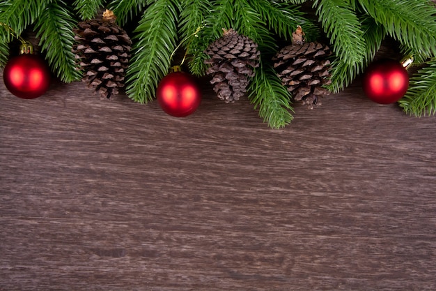 Decorazioni natalizie con rami di abete palla di Natale e pino su fondo in legno