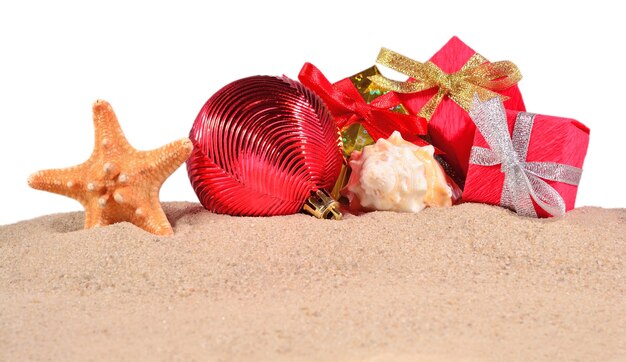 Decorazioni natalizie conchiglie e stelle marine su una spiaggia di sabbia su sfondo bianco