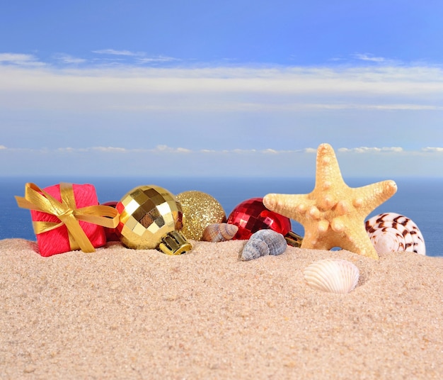 Decorazioni natalizie, conchiglie e stelle marine su una spiaggia di sabbia sullo sfondo del mare