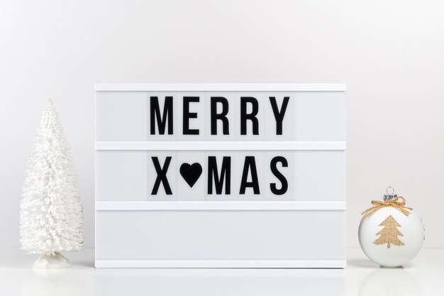 Decorazioni natalizie e lightbox con testo MERRY XMAS sul tavolo bianco