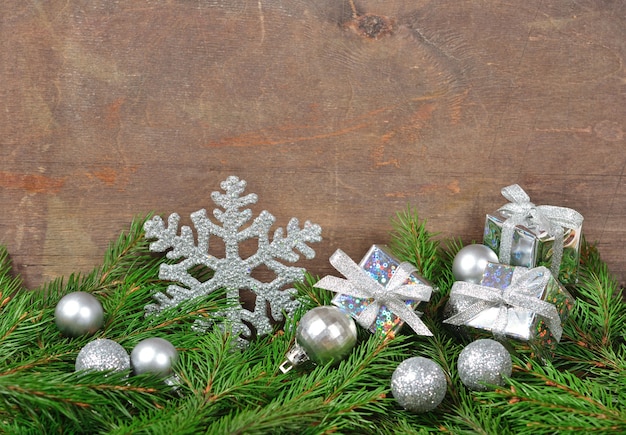 Decorazioni natalizie in argento e ramo di abete rosso su fondo in legno