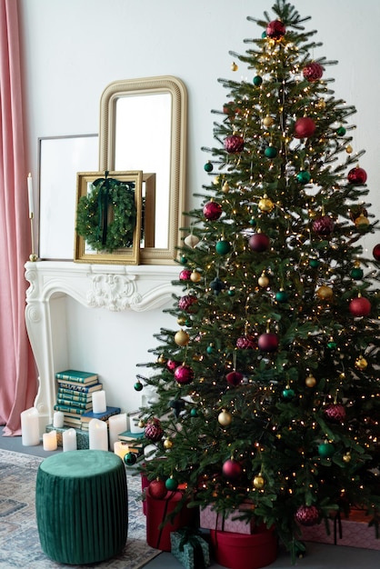 Decorazioni natalizie moderne. L'interno è decorato con ghirlande, candele, un camino, ghirlande di Natale e un albero di Capodanno con regali, scatole regalo in stile contemporaneo. Messa a fuoco selettiva morbida.