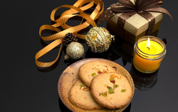 Decorazioni natalizie per la tavola con biscotti a buccia d'arancia, una confezione regalo e una candela profumata.