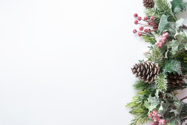 Decorazioni natalizie, rami di abete in stile, pigne su sfondo bianco.