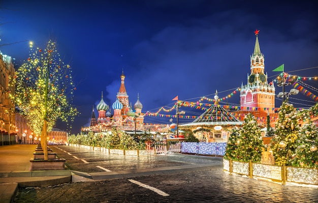 Decorazioni per alberi di Natale sulla Piazza Rossa, cupole della Cattedrale di San Basilio e Torre Spasskaya in una notte d'inverno