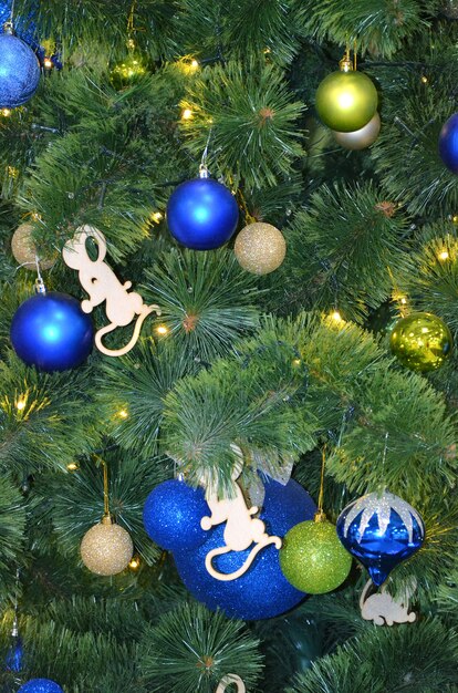 Decorazioni per il nuovo anno palline blu e verdi su un finto albero di natale da vicino e una ghirlanda luminosa