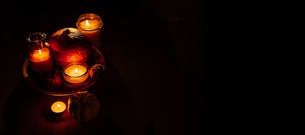 Decorazioni per la casa del Ringraziamento autunnale con zucche e candele accese sul tavolo Decorazioni scure con striscioni lunatici con zucca e candele