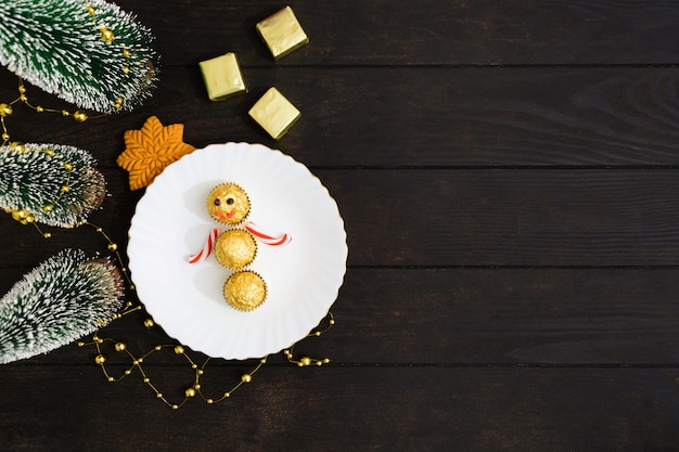 Decorazioni per la tavola di Natale con pupazzo di neve di caramelle sul piatto con l'albero di Natale