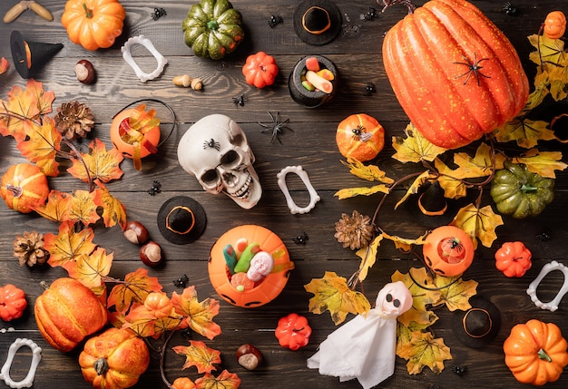 Decorazioni per le feste di Halloween con zucche e caramelle su sfondo di legno nero