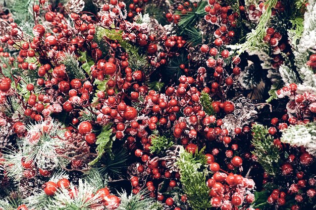 Decorazioni per le feste di Natale. Brunch di abete di Natale con bacche rosse e coni nella neve scintillante vicino alla trama. Messa a fuoco poco profonda. Concetto di carta da parati natalizia