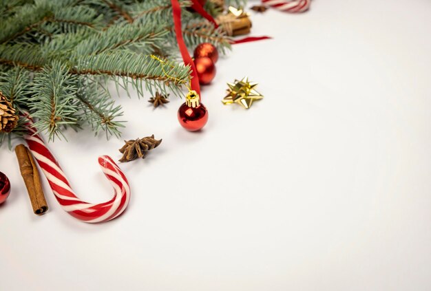 Decorazioni per le vacanze di Capodanno o Natale Rami dell'albero di Natale palline rosse coni nastri rossi e fiocco bastoncini di cannella anice stelle e lecca-lecca su sfondo bianco Posto per il testo