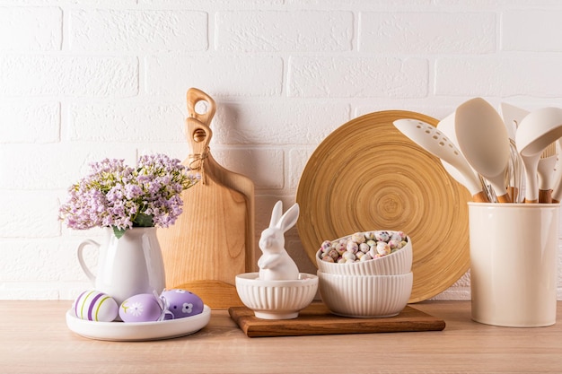 Decorazioni per le vacanze di Pasqua su un bancone di cucina in legno con utensili da cucina ecologici e uova conigli di ceramica concetto di Pasqua