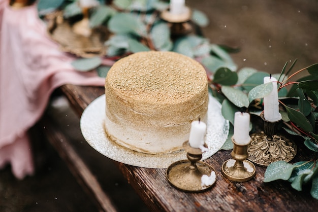 Decorazioni per matrimoni con una torta dorata su una panca di legno sullo sfondo di una cascata