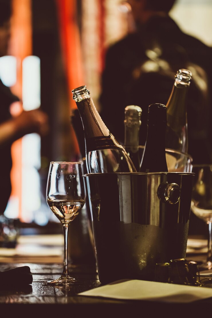 Degustazione di vini: su un tavolo di legno c&#39;è un secchio d&#39;argento per rinfrescare i vini con le bottiglie aperte.