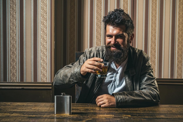 Degustazione e concetto di degustazione uomo barbuto con bicchiere di whisky