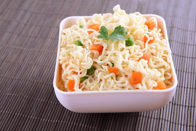 Degusti noodles istantanei con verdure in ciotola sul tavolo in primo piano
