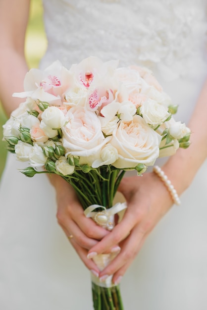 Delicato bouquet da sposa di latte e rose bianche, orchidee nelle mani della sposa