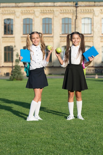 Delizia della dieta Bambini felici tengono mele e libri Merenda scolastica Dieta e alimentazione sana Alimenti dietetici Dieta per la salute Abitudini alimentari Alimentazione sana a scuola Dieta intelligente